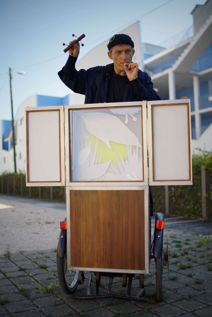 Un castelet monté sur un vélo permet au comédien placé derrière de faire de la musique avec des instruments qu'il a des les maisn et la bouche.